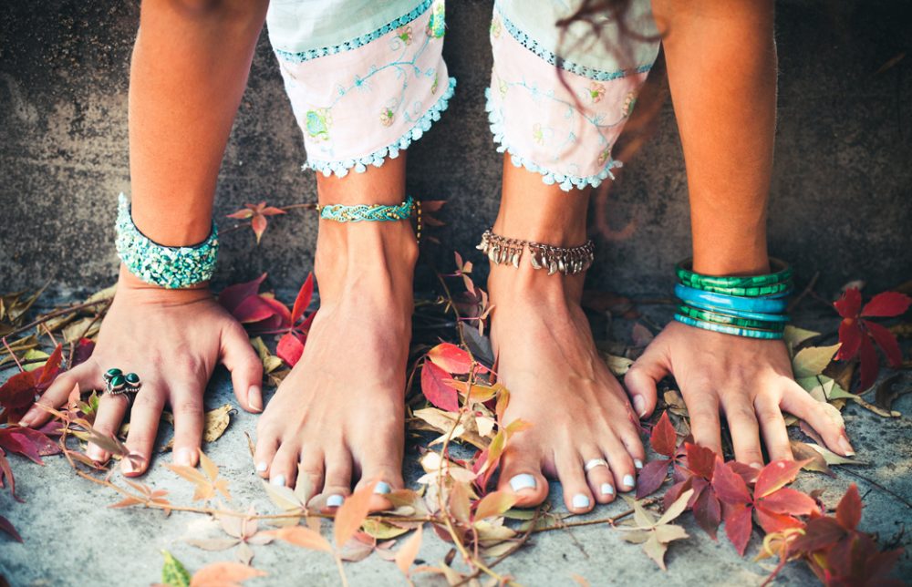 落ち葉の上で裸足で前屈をしている女性の足もとだけ