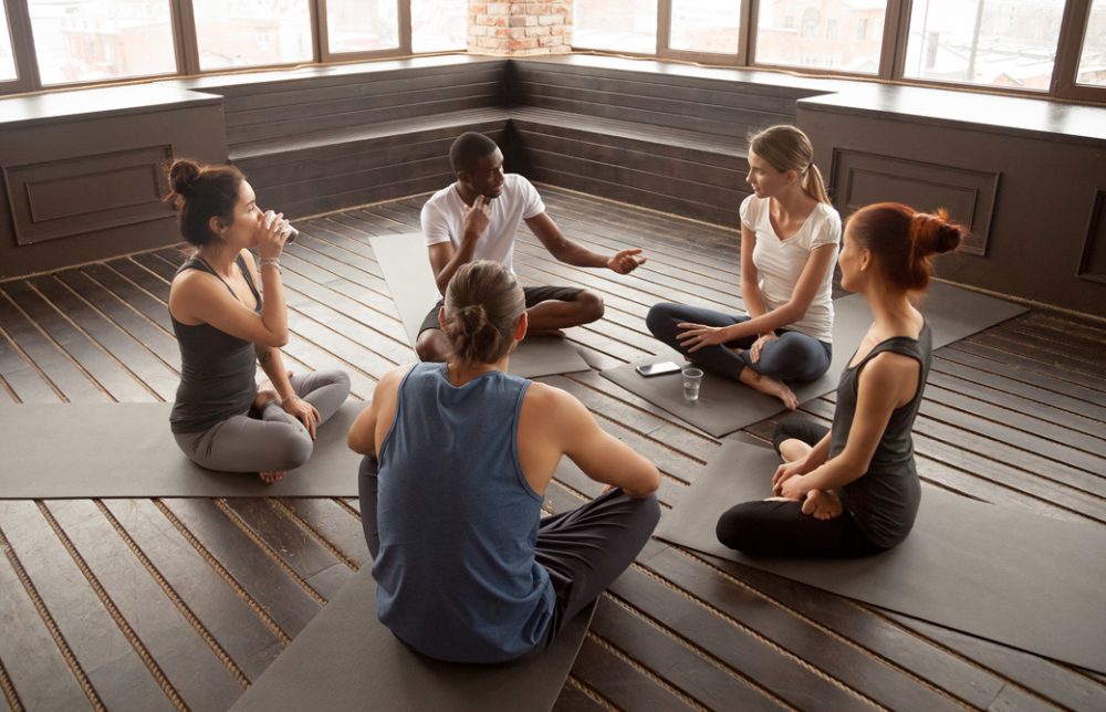 5人のヨギーが輪になってサットサンガをしている