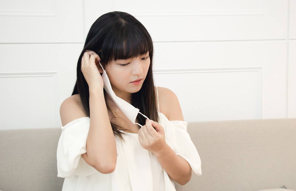 マスクを付けようとしている黒髪の女性