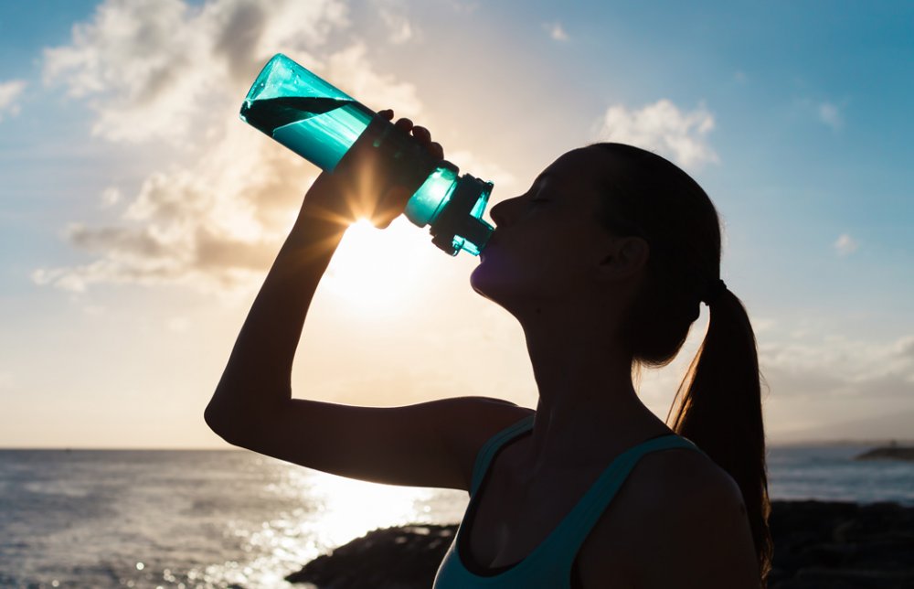 ウォーターボトルから水を飲んでいる女性の横顔のシルエット