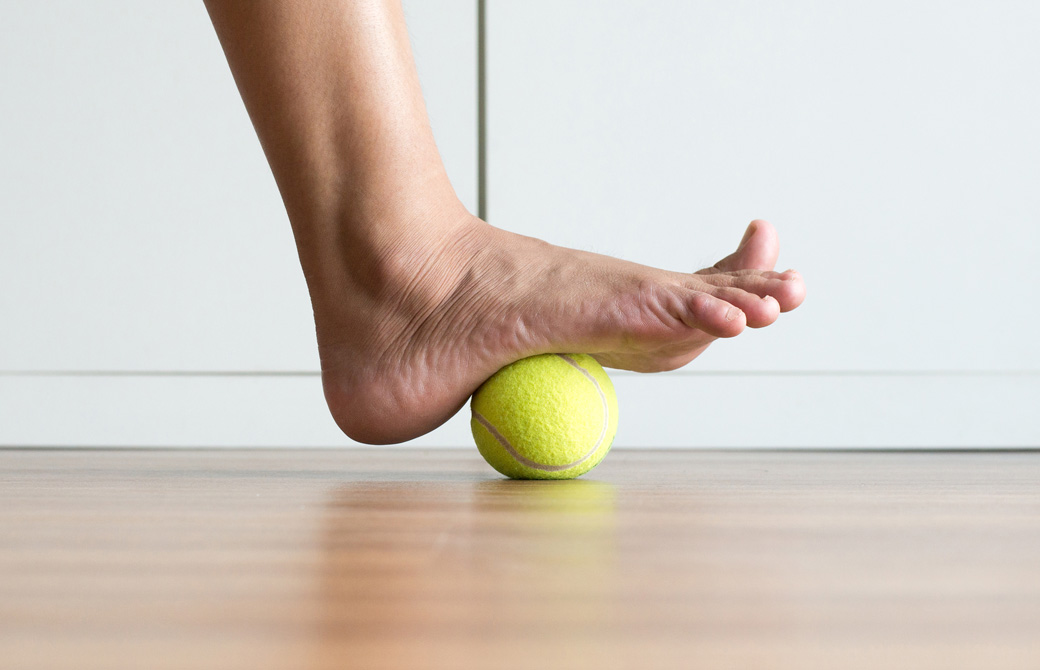 テニスボールに裸足の片足を乗せているところ