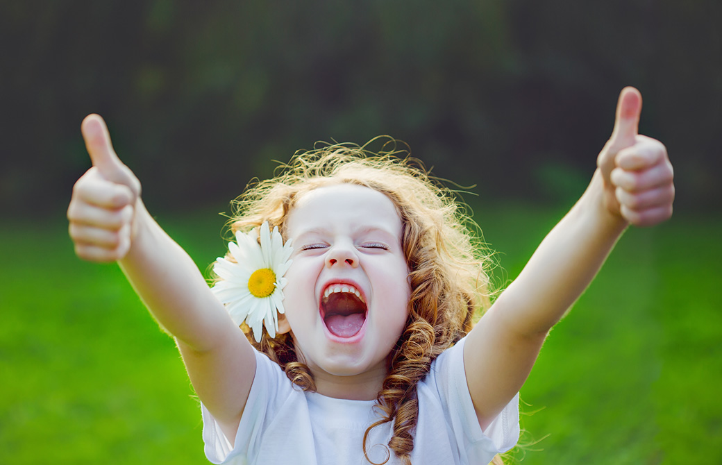 花を耳にさしてオーケーサインで笑う子ども