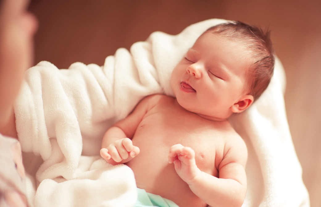 お母さんに抱かれて眠る新生児