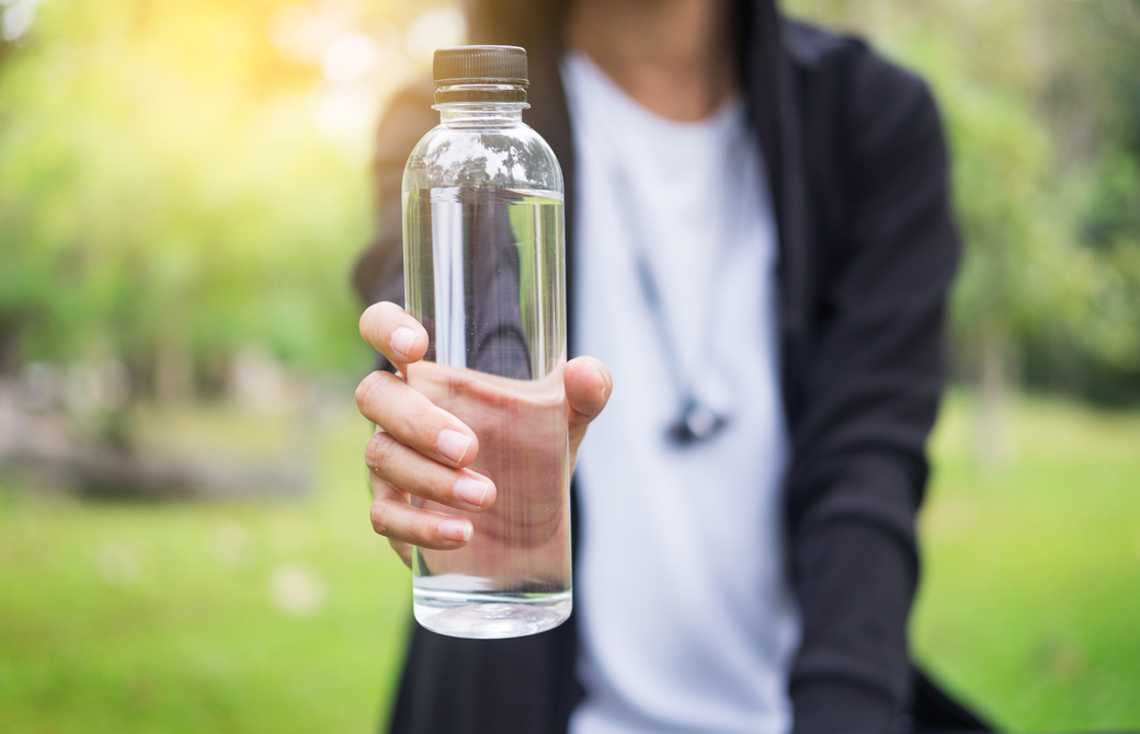 水のボトルを差し出している女性の上半身