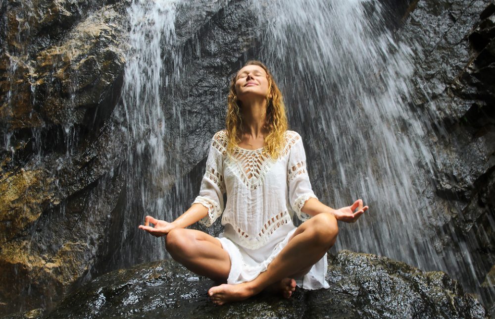 女性が滝に打たれて瞑想をしている