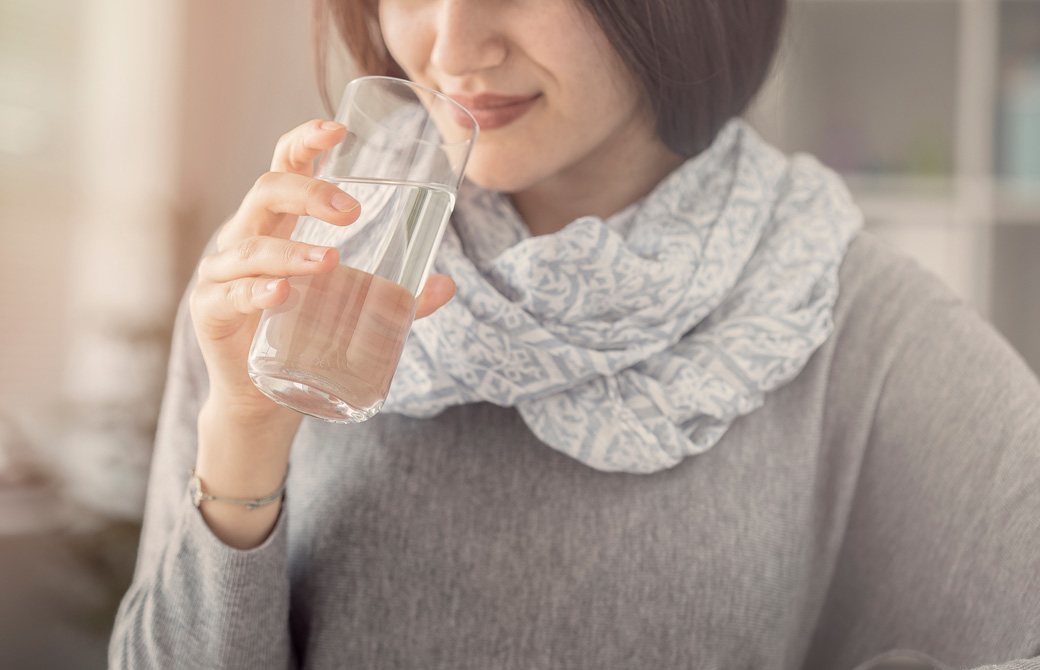 首にスカーフを巻いた女性が水を飲んでいる