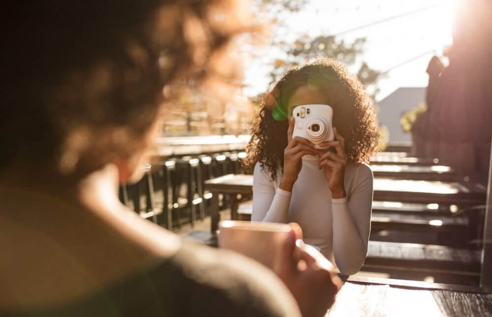インスタントカメラで友達を撮影している女性