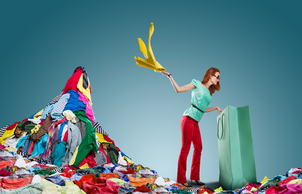 大きな紙袋から洋服を引っ張り出して放り投げて積んでいる女性