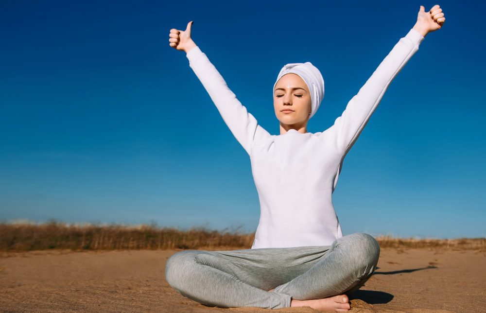 女性が青空のもとクンダリーニヨガを行っている