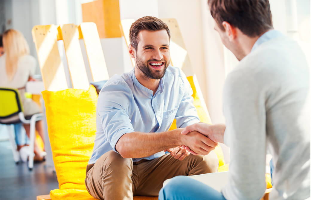 ひげの男性が笑顔で握手をしている