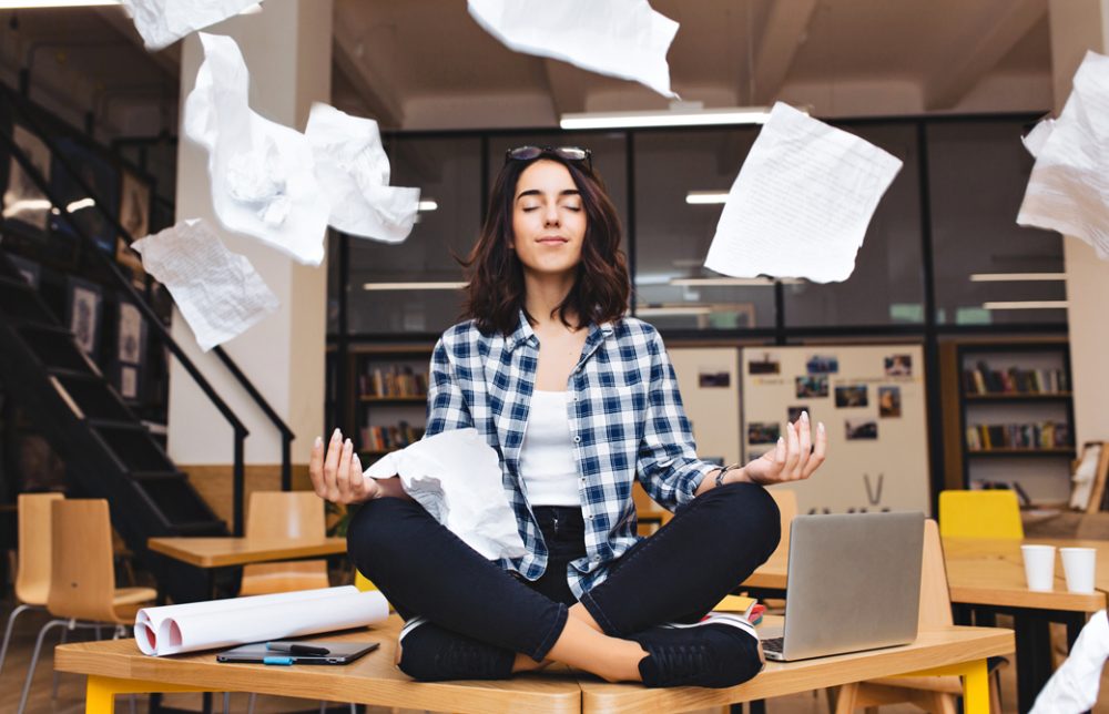 飛び交う書類の間で瞑想をして心を落ち着かせている女性