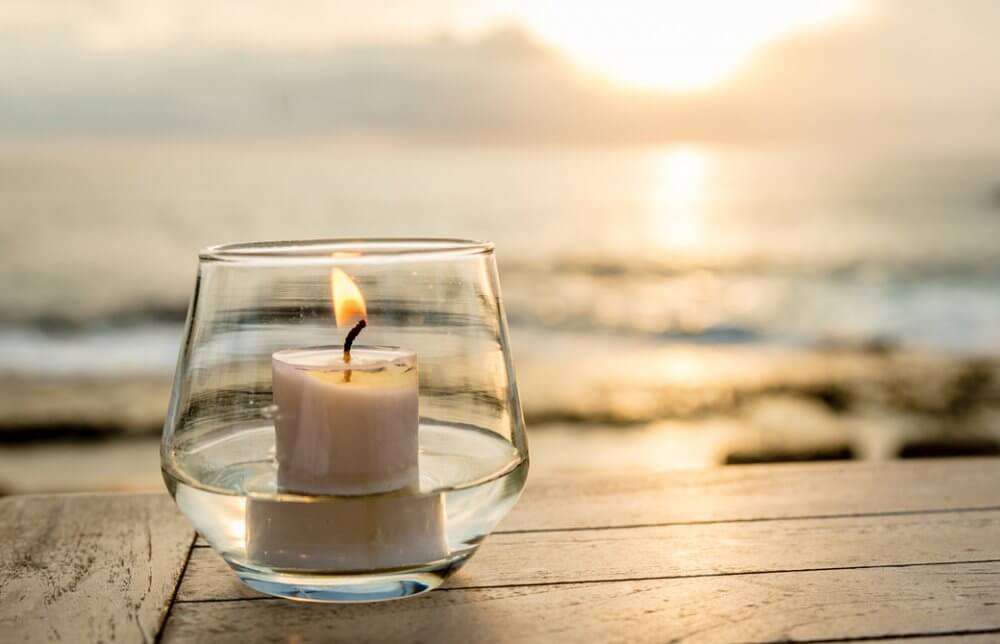 海辺で灯されたグラスの中のキャンドル