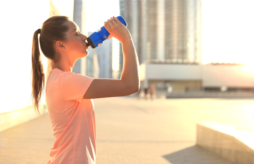 屋外で水のボトルから水を飲んでいる女性の横姿