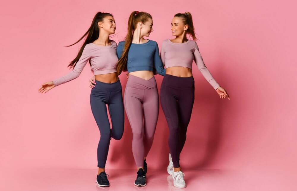 カラフルなヨガウエェアを着た3人の女性が楽しそうに歩いている