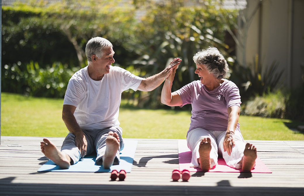屋外の芝生の上で手をつないで微笑み合う男女のシニア