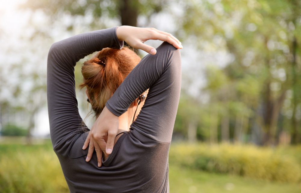 女性が公園で肩のストレッチをしている後ろ姿