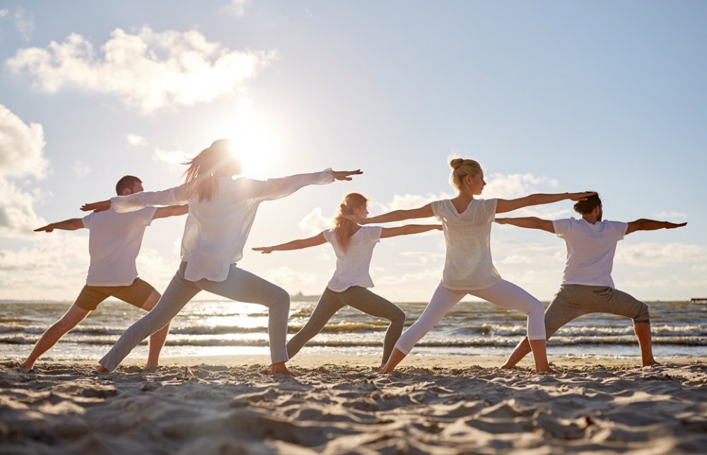 海辺で戦士のポーズ2をする男女