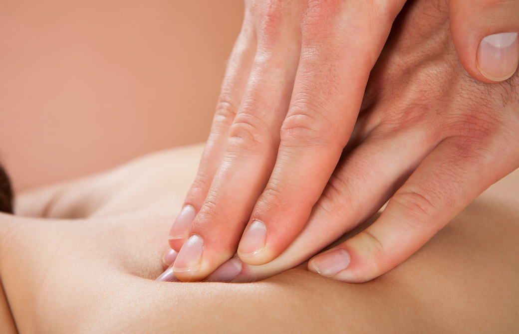 女性の背中を指圧している人の両指先