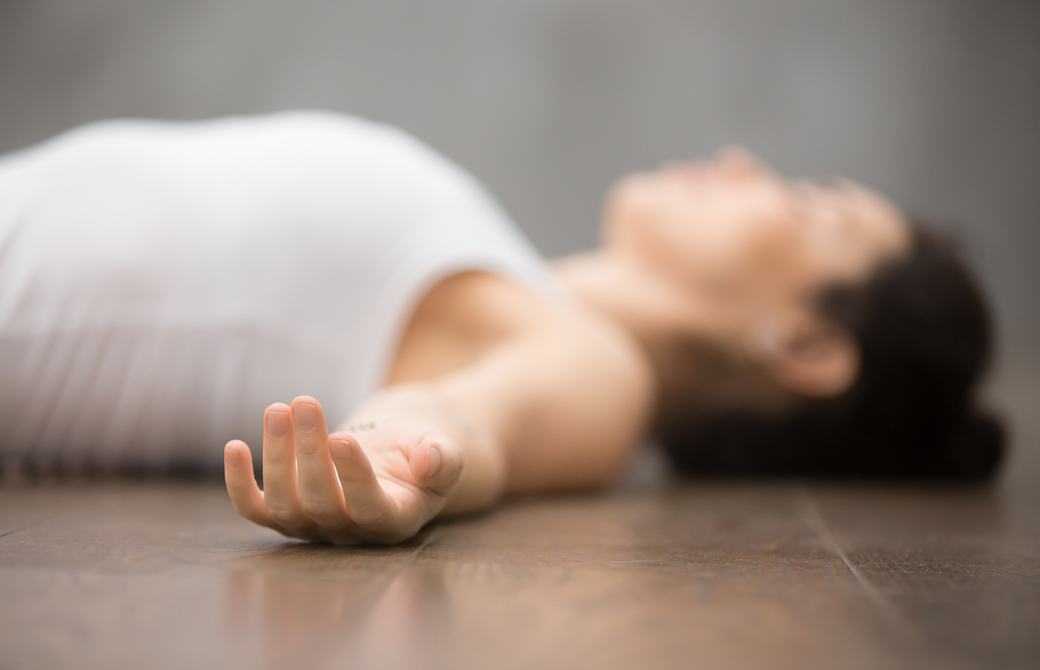 床でシャバアサナをしている女性を横から見たところ