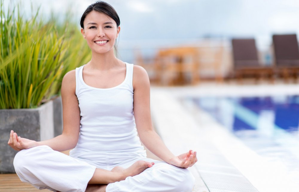 プールサイドで胡座の女性が微笑んでいる