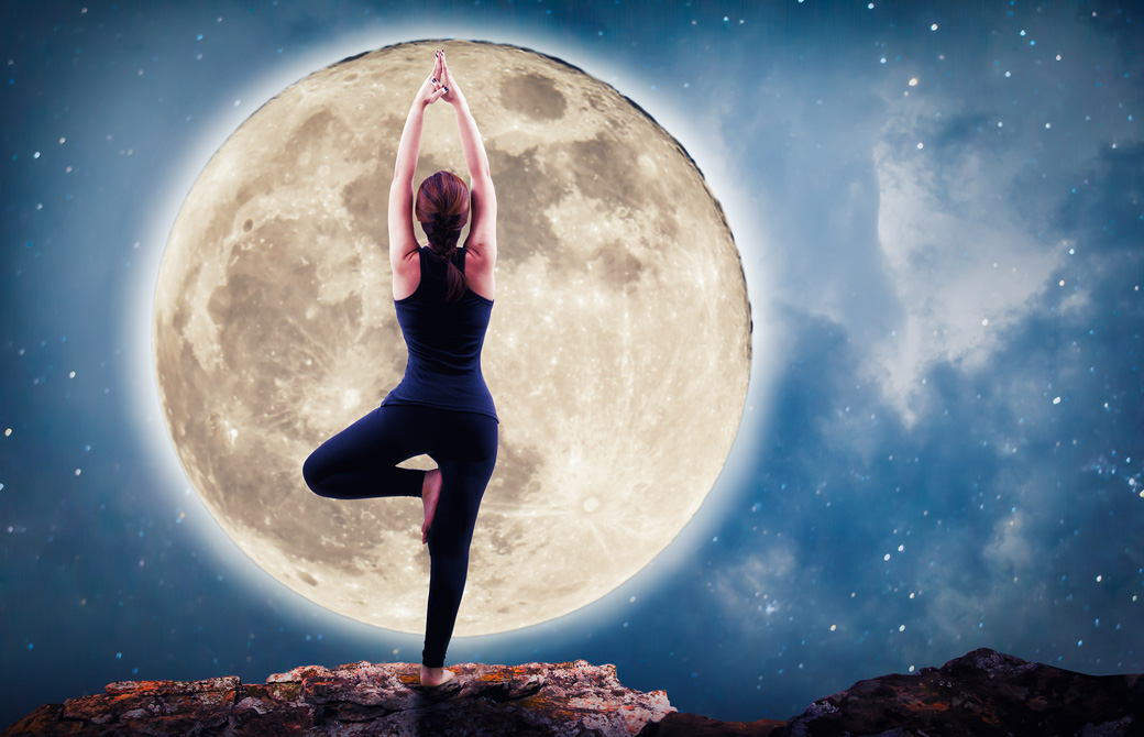 満月に向かって木のポーズをする女性