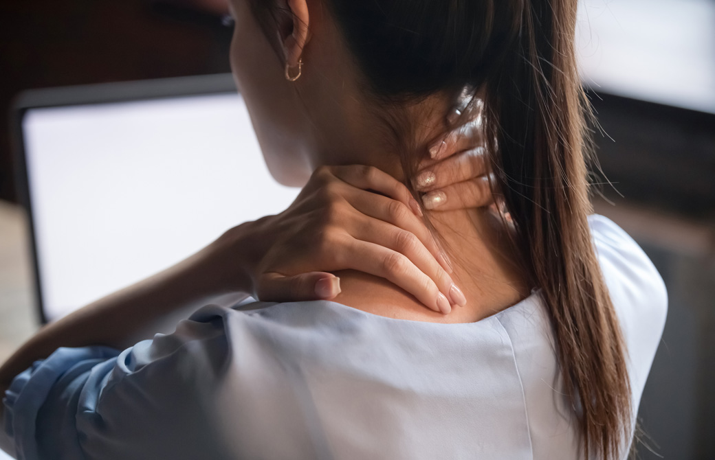 首の後ろ側を両手で押さえる女性の後ろ姿