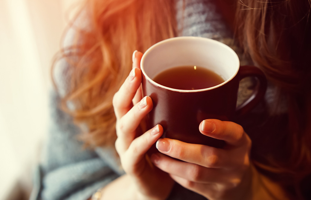 ホットドリンクのマグカップを手にした女性