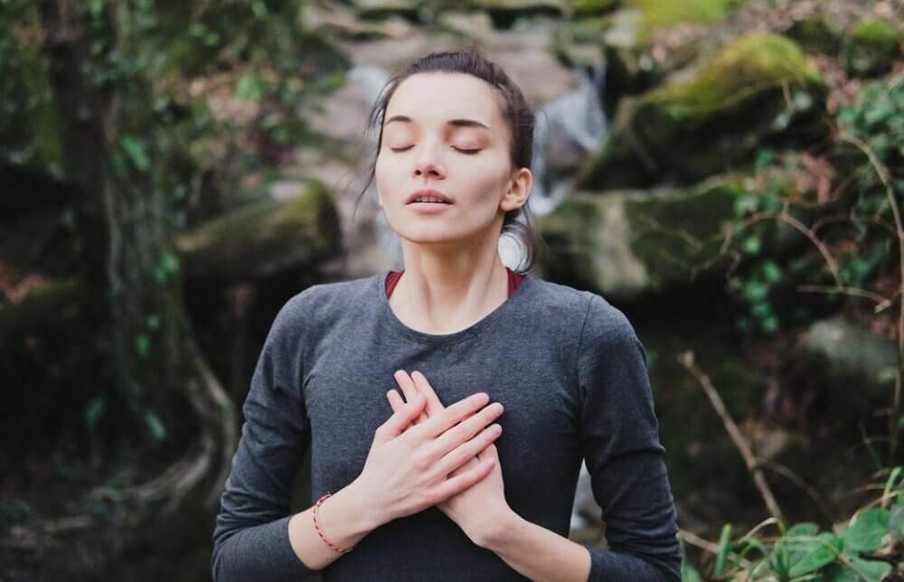 両手を胸に当てて目を閉じ呼吸をしている女性