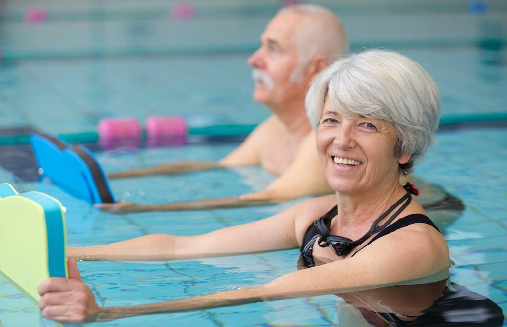 ビート板を持ってプールでエクササイズをする老夫婦