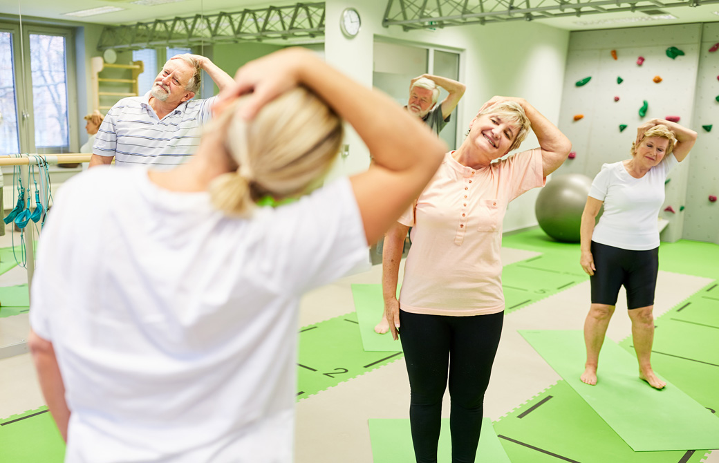 インストラクターと一緒に首のストレッチをしているシニア
