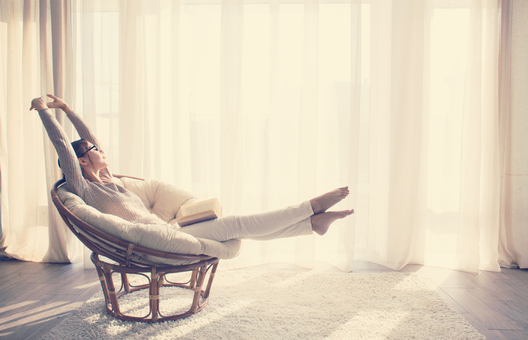 窓際でソファに座り大きく体を伸ばしている女性