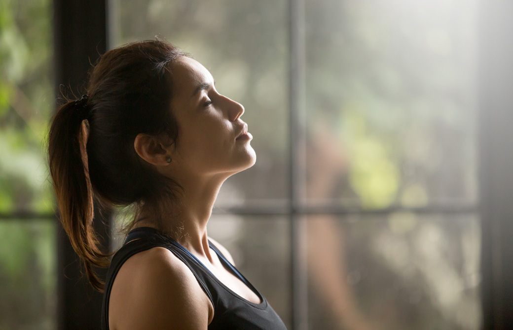 室内で目を閉じ呼吸をしている女性の横顔