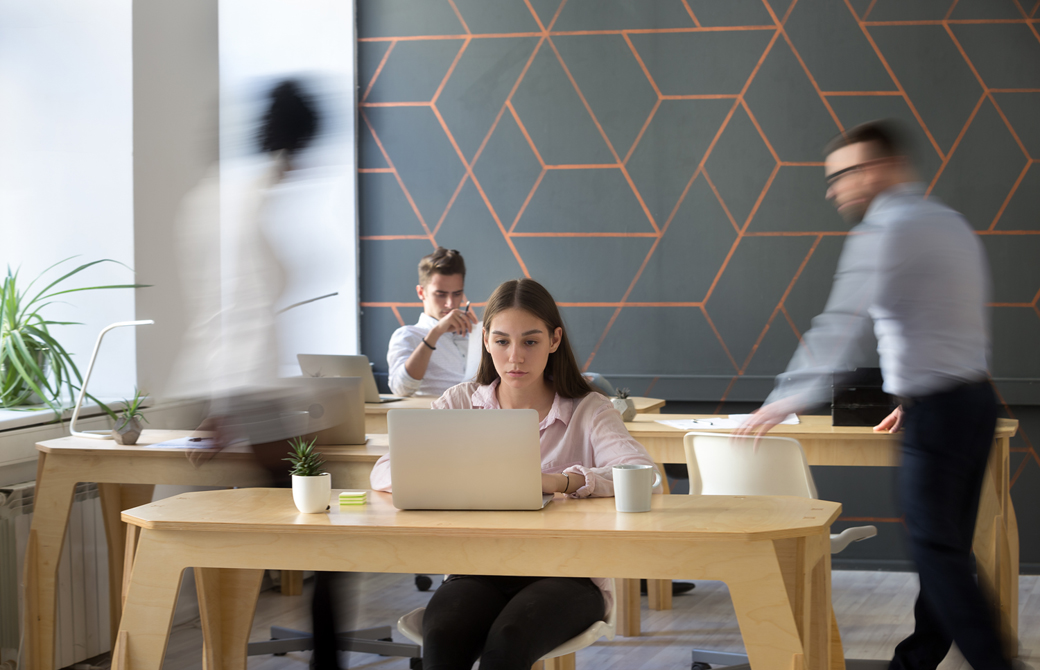 女性がオフィスのテーブルでPCに向って集中しているところ
