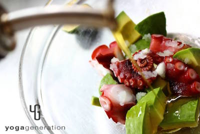 ボウルのアボカドとタコにオリーブオイルを加えているところ