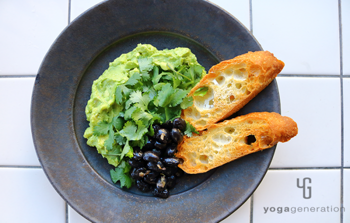 黒い器に入れた黒豆のスパイシー・ニンニク炒め和風アボカド・ディップ添え