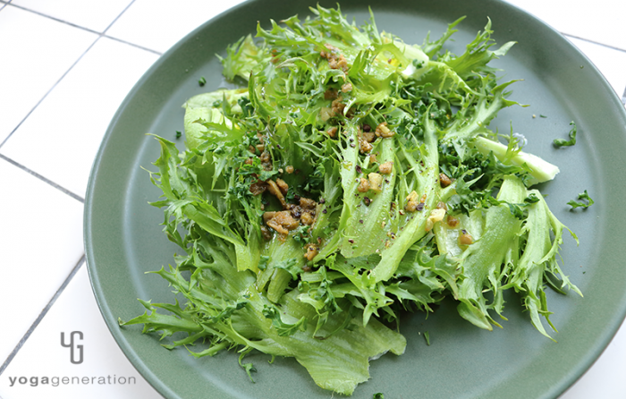 深いグリーンの皿に盛り付けたグリーンオリーブとアンチョビのガーリックオイル・サラダ