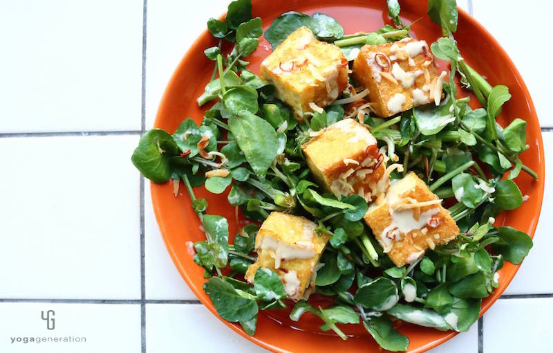 オレンジの皿に乗ったクレソンと厚揚げのサラダ