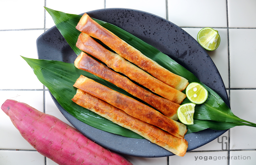 黒い皿に広げた葉に盛りつけたサツマイモ味噌スティック