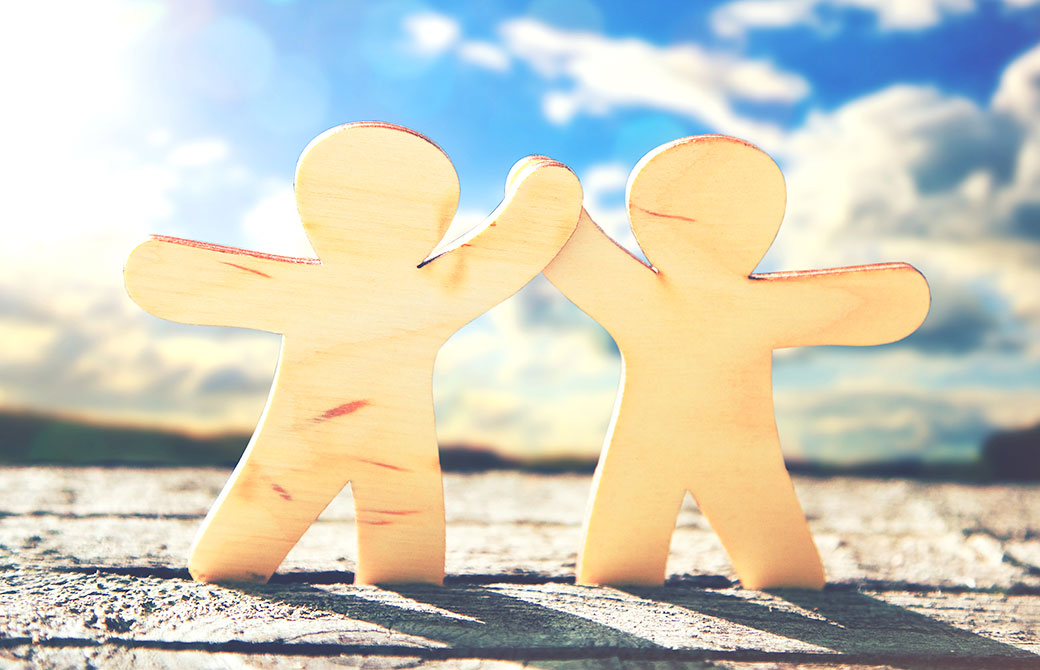 青空の下2人で仲良く手を繋いでいる画像