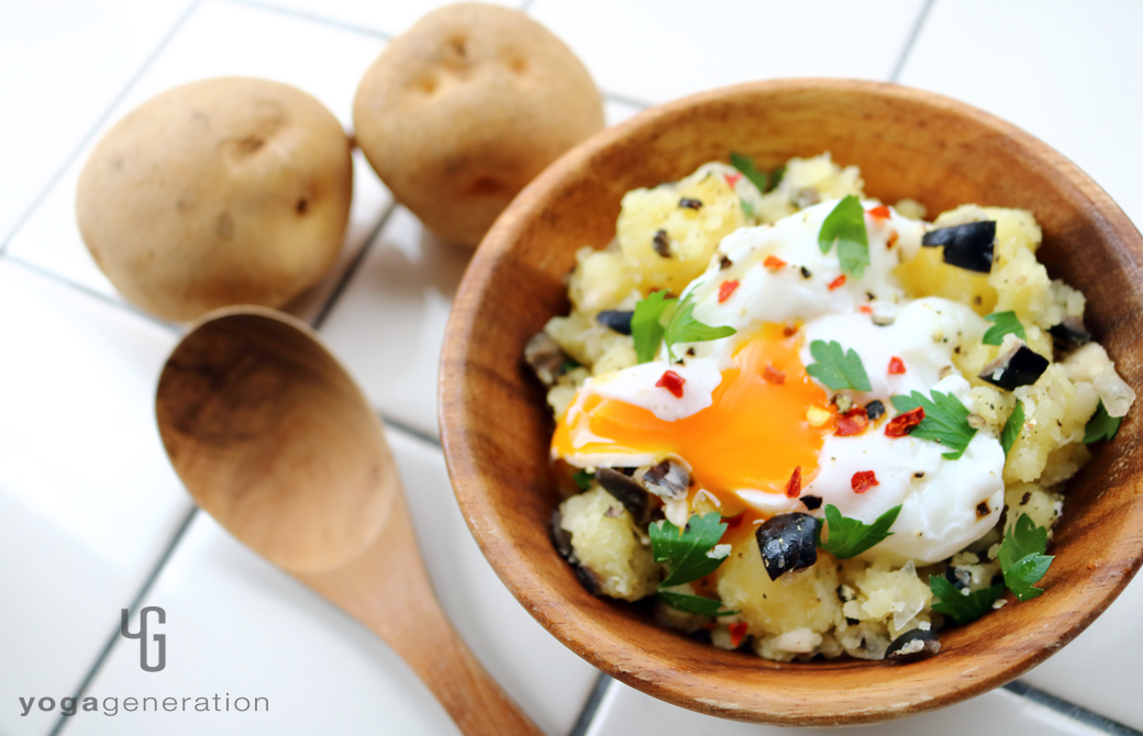 温泉卵を添えて木の皿に盛りつけたラッキョウと黒オリーブのポテトサラダ