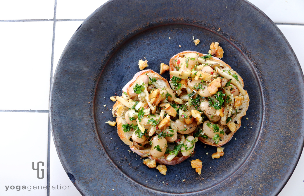 パンの上に盛りつけたシメジと白インゲン豆のハーブマリネ