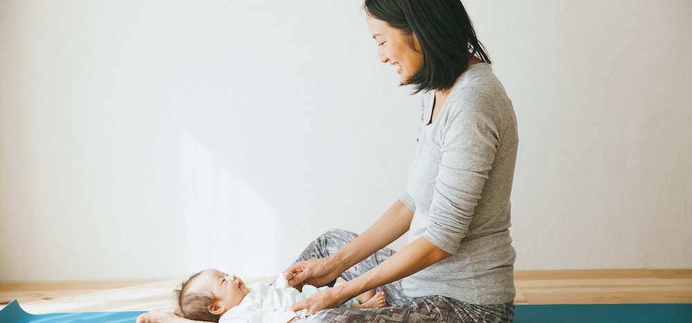 ヨガマットの上で赤ちゃんと見つめあうサントーシマ香先生