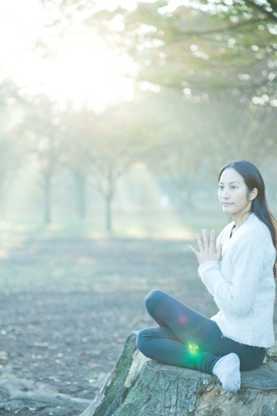 切り株に座り合掌するサントーシマ香先生