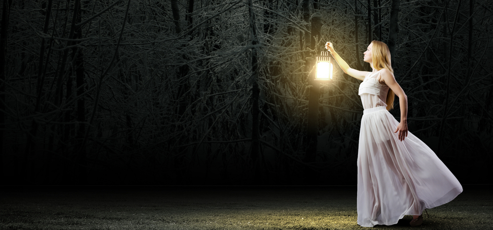 暗がりでランプを持つ女性