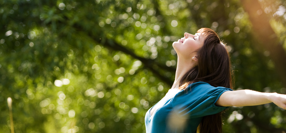 森の中で大きく息を吸う女性
