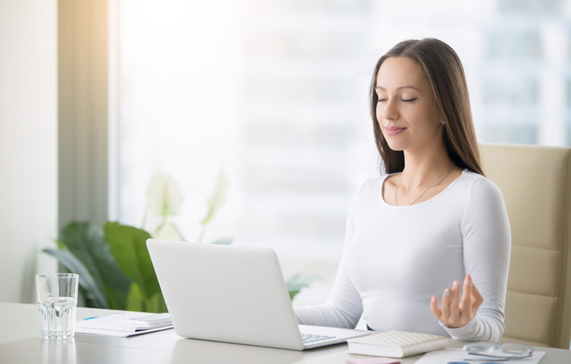 デスクで目を閉じ呼吸をしている女性