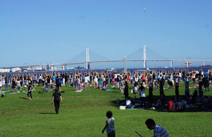 ベイブリッジが見える芝生の上でヨガをしている大勢の人々