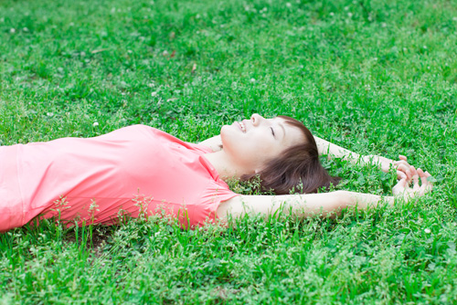 芝生で寝転がる女性