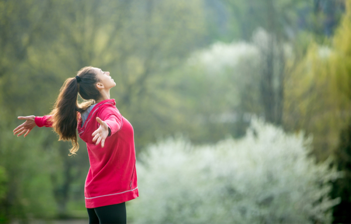 自然の中で大きく深呼吸する女性