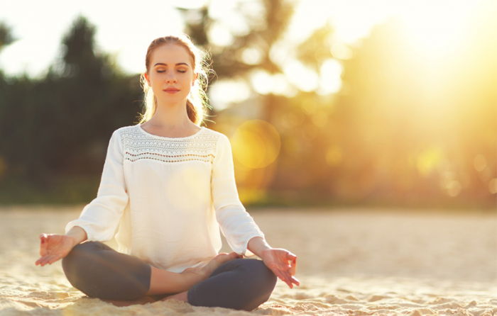 女性が砂浜に座り瞑想している